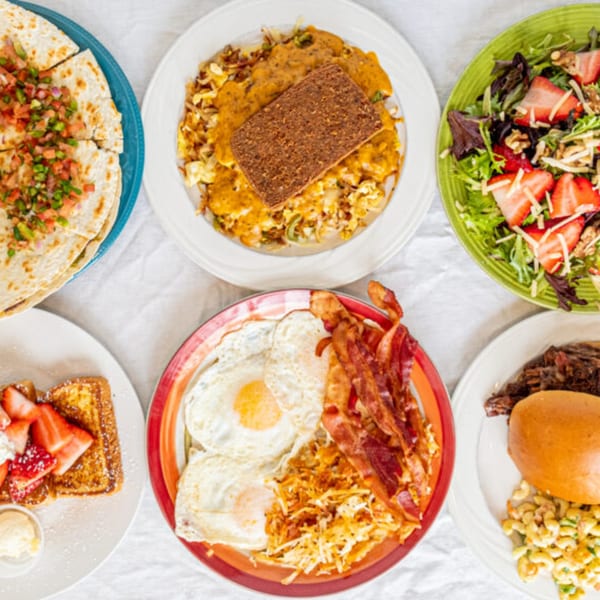 Overhead view of five diner plates including quesadillas, breakfast platters, and a strawberry salad.