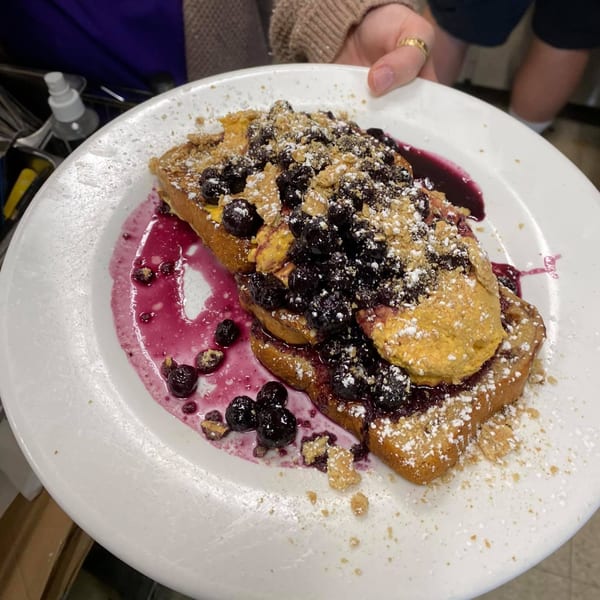 French toast topped with blueberries, peanut butter, powdered sugar, and graham cracker crumbles.
