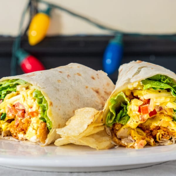 Two Green Street Grill wraps, filled with chicken, lettuce, cheese, and tomatoes, served with chips.