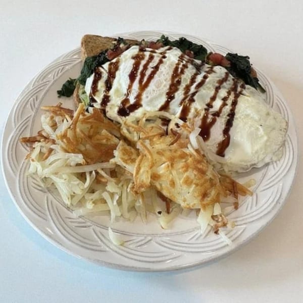 Green Street Grill's breakfast plate with hash browns, eggs, and toast topped with spinach and sauce.
