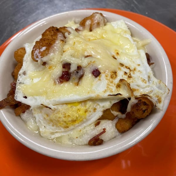 A diner breakfast bowl with tater tots, eggs, melted cheese, and bacon bits.