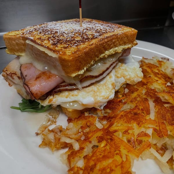 A Monte Cristo sandwich with hash browns on a white plate at Green Street Grill.